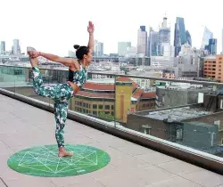 woman doing yoga on rooftop overlooking city skyline